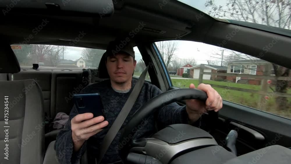 Irresponsible driver potentially breaking the law by texting on his phone whilst driving.