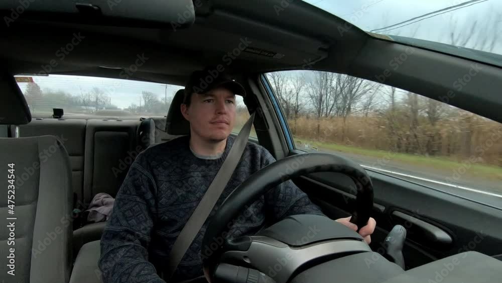 A man in black t-shirt driving the car in the snowy countryside, southeast Michigan on the road in a green background in USA. A man in black t-shirt driving the car in the snowy countryside, southeast Michigan on the road in a green background in USA.