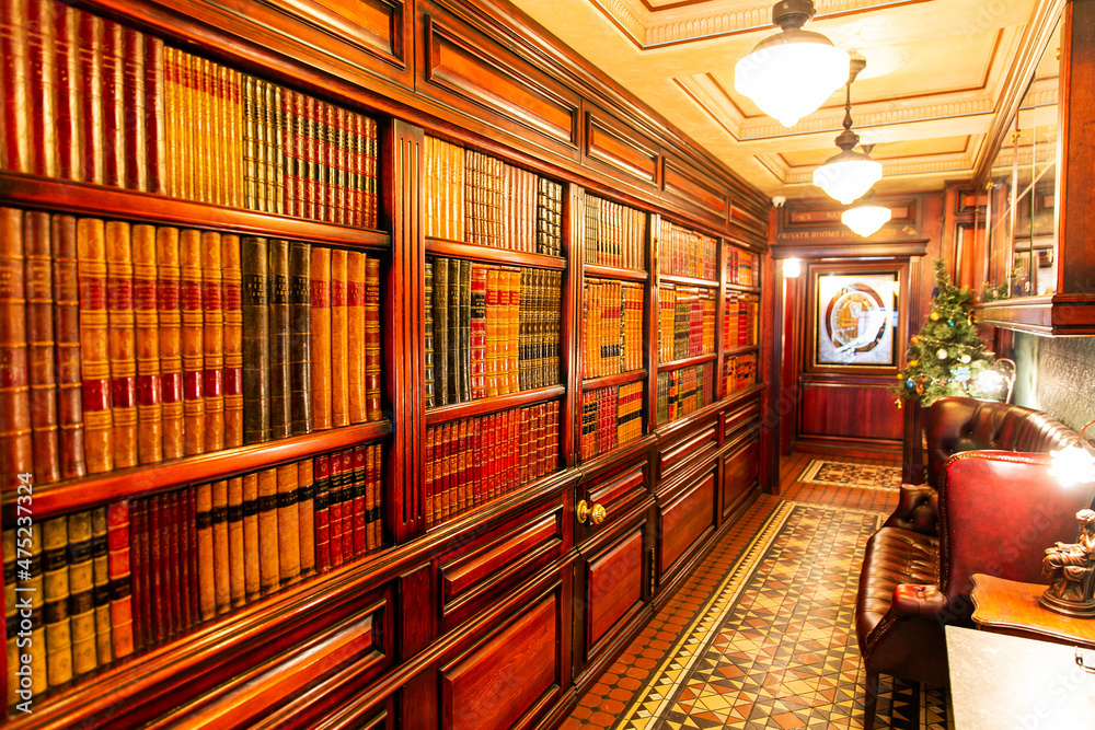 Classical library room with leather armchair, wooden table and bookcase. English classic style