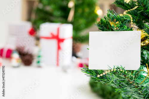 blank wishing card holding on pine tree with christmas and new year decoration on background