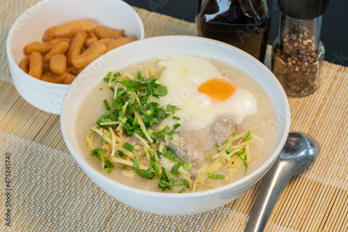 Porridge rice gruel with egg in white bowl Chinese Traditional breakfast with deep-fried dough stick.