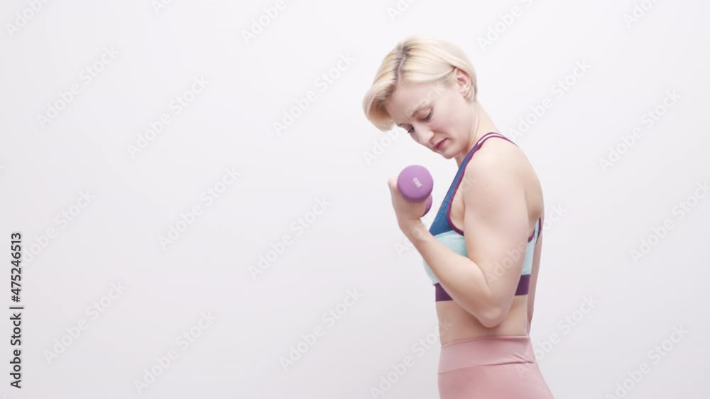 Young caucasian athletic woman exercises, Lifts dumbbell in a sports outfit - Medium Shot Young caucasian athletic woman exercises, Lifts dumbbell in a sports outfit - Medium Shot