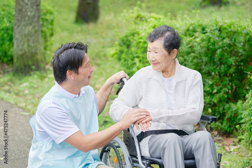 介護士と車椅子に乗る高齢者　屋外