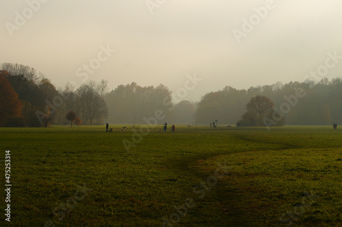 Misty autumn atmosphere in Niddapark Frankfurt. Many dog owners are out and about. photo