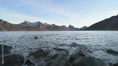 Water Splashing On The Rocks In Senja Mefjordvaer With Peaceful Mountain View In The Background, Norway. - Static Shot  photo