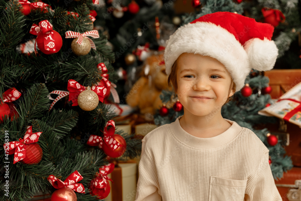 A child with Santa Clause hat helps to decorate Christmas tree A child with Santa Clause hat helps to decorate Christmas tree