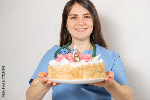 The doctor or nurse holds a birthday cake with the number six for the anniversary of the opening of the clinic