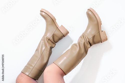 A female legs in brown leather boots upside down on white background.