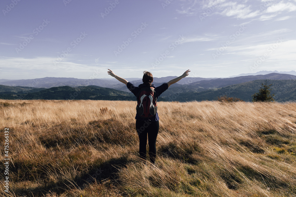 A girl with a backpack enjoys the autumn mood view of the mountains A girl with a backpack enjoys the autumn mood view of the mountains