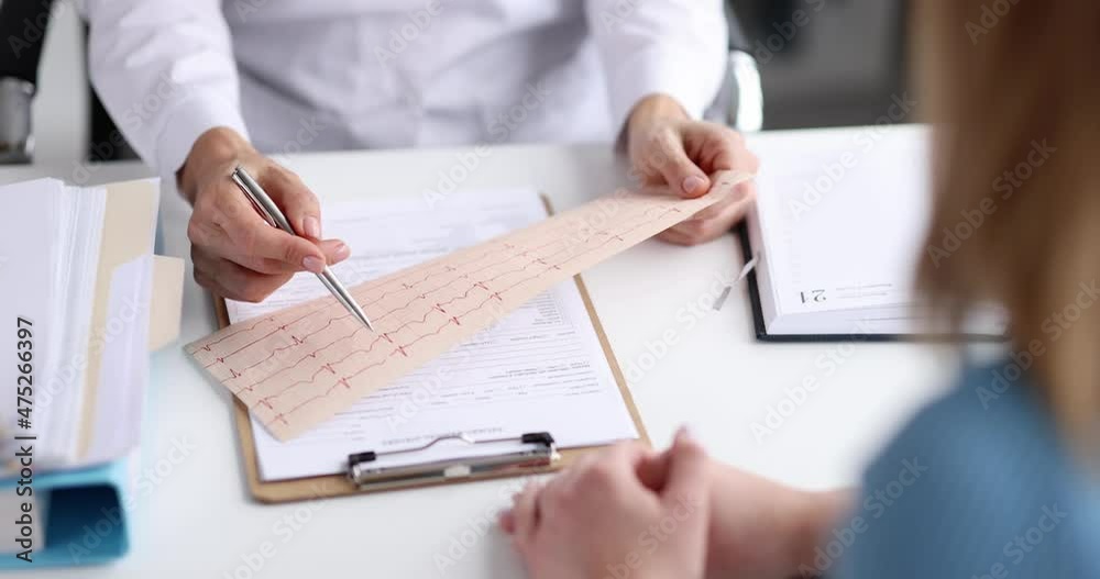 Doctor cardiologist examining ecg tape in front of patient at clinic 4k movie slow motion Doctor cardiologist examining ecg tape in front of patient at clinic 4k movie slow motion