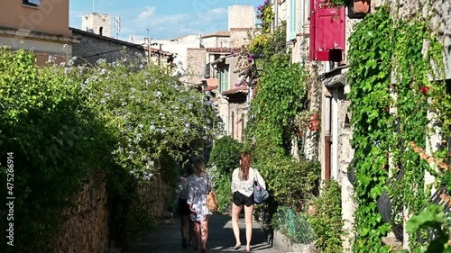 Street view of Antibes, France. Narrow street with a lot of greenery, old traditional buildings, three walking women photo