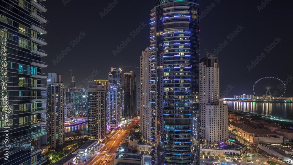 Fototapeta premium Panoramic view of the Dubai Marina and JBR area and the famous Ferris Wheel aerial night timelapse