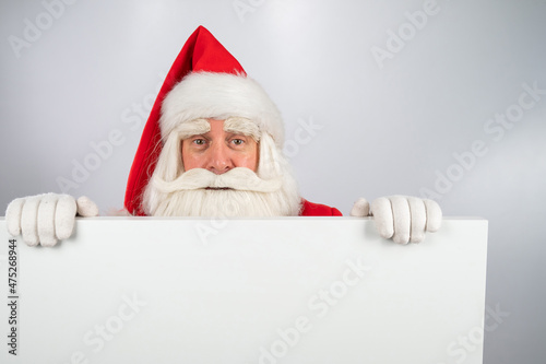 Santa Claus peeks out from behind an ad on a white background. Merry Christmas. © Михаил Решетников