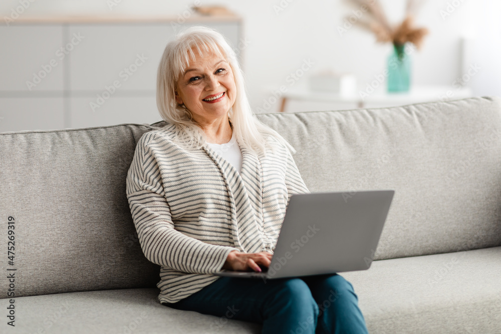 Mature woman sitting on couch and working on computer Mature woman sitting on couch and working on computer
