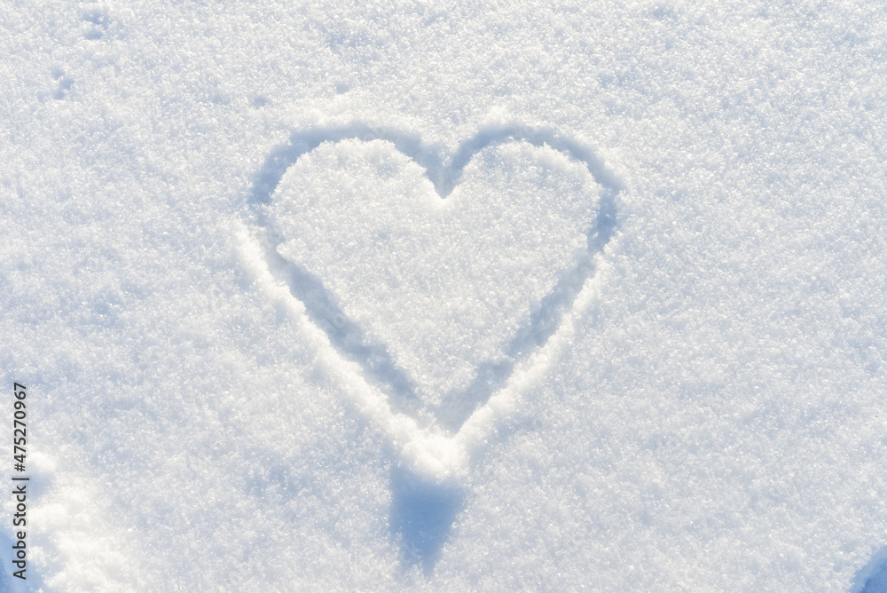One hand drawn heart shape in the fresh snow.Top view,closeup,copy space. One hand drawn heart shape in the fresh snow.Top view,closeup,copy space.