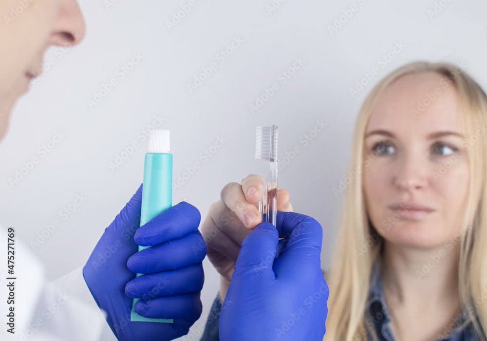 Clean tongue. The doctor teaches the patient how to clean the tongue properly. Dentist consultation. The blonde girl is trained in proper oral hygiene. Man and woman isolated on white background Clean tongue. The doctor teaches the patient how to clean the tongue properly. Dentist consultation. The blonde girl is trained in proper oral hygiene. Man and woman isolated on white background