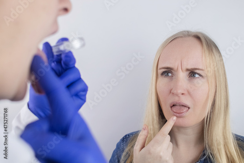 Clean tongue. The doctor teaches the patient how to clean the tongue properly. Dentist consultation. The blonde girl is trained in proper oral hygiene. Man and woman isolated on white background