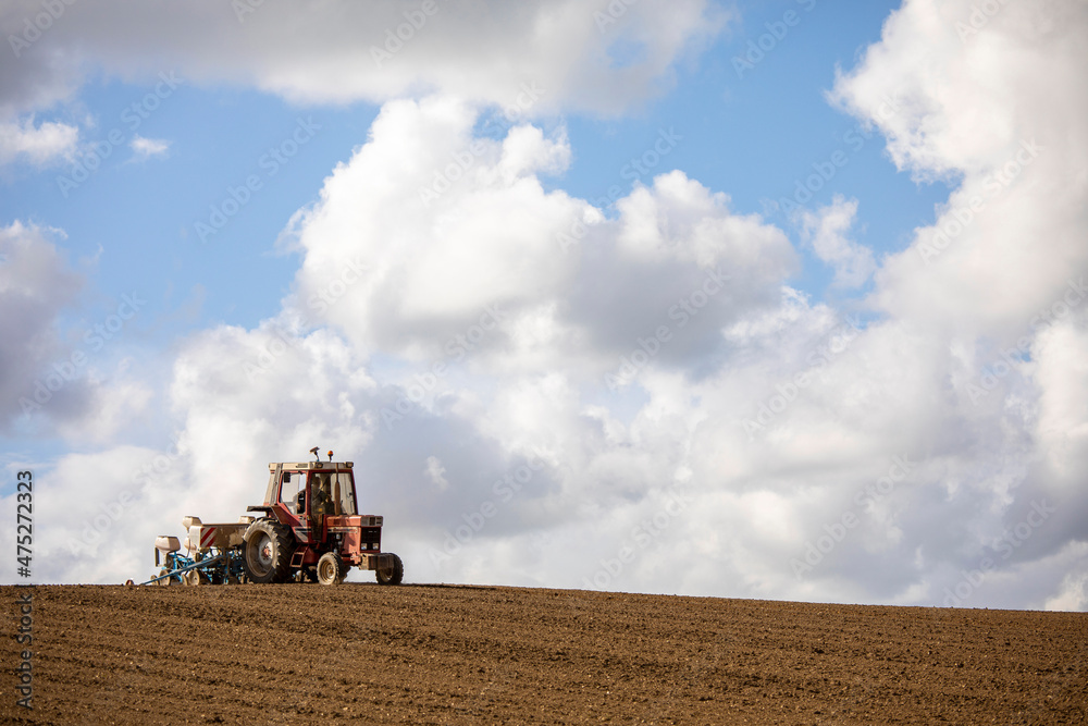 Fototapeta premium Paysan au volant de son tracteur labourant les champs au printemps.