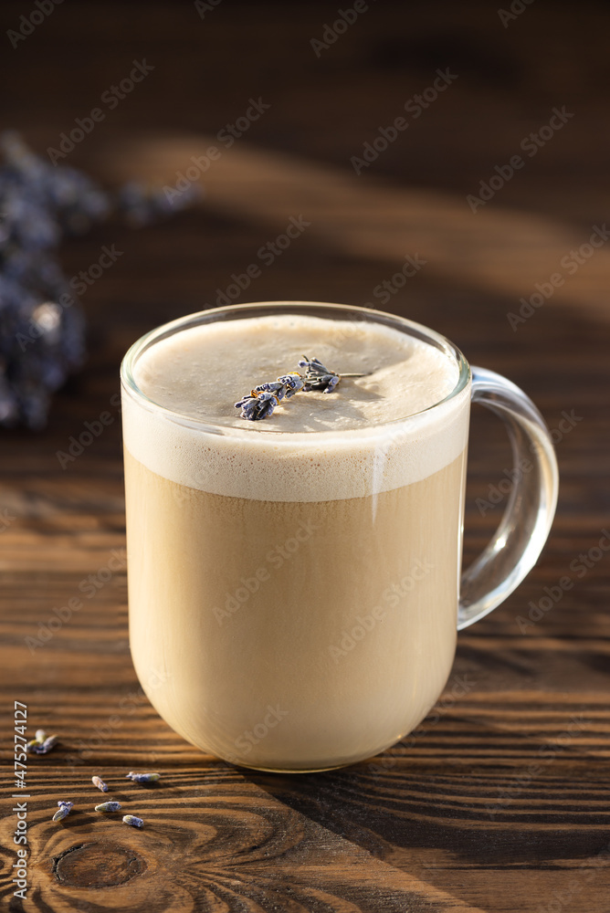 Raf coffee with lavender and coconut milk in a glass mug on a wooden table. Russian drink. Hard, natural light. Raf coffee with lavender and coconut milk in a glass mug on a wooden table. Russian drink. Hard, natural light.