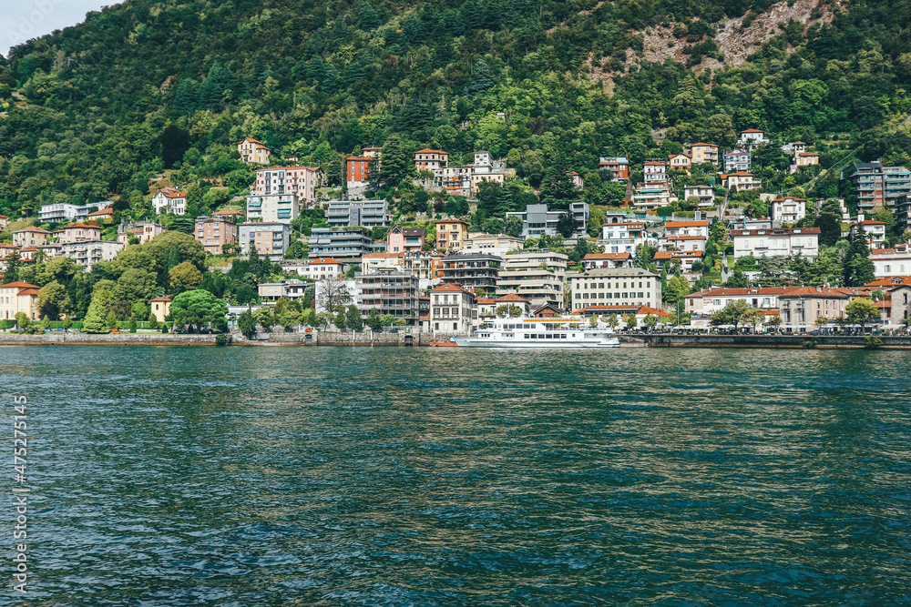 Panoramic view of big houses over hill town by the lake shore in northern Italy 