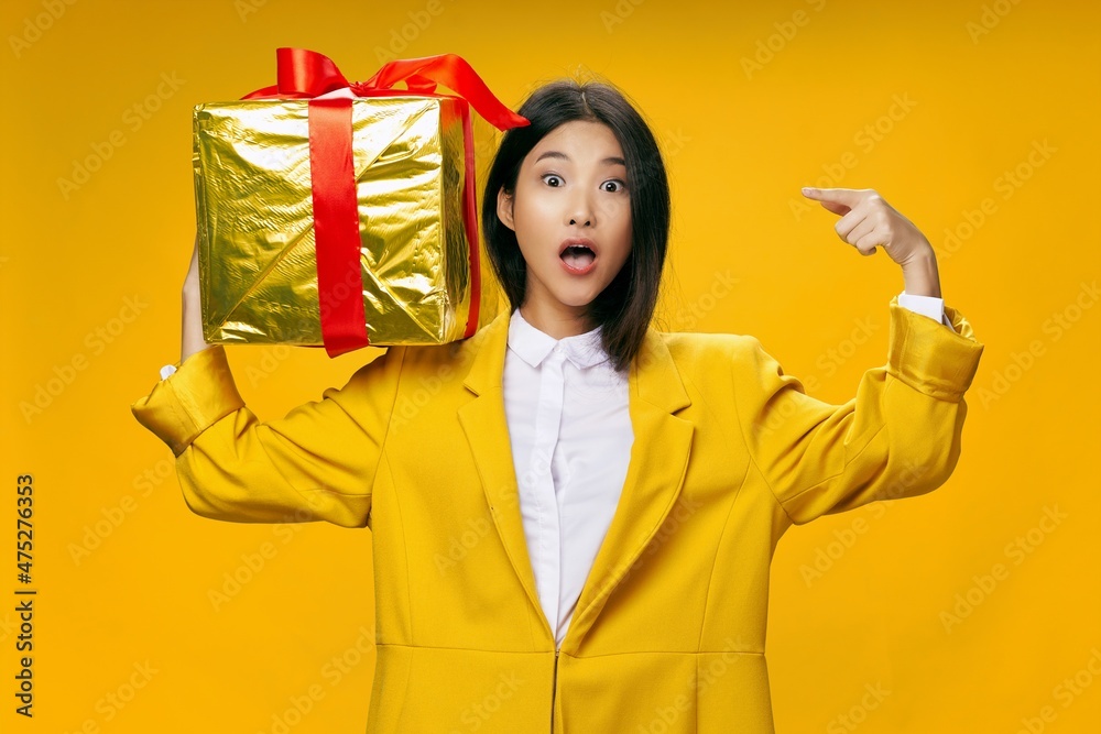 woman holding a gift holiday surprise holiday yellow background woman holding a gift holiday surprise holiday yellow background