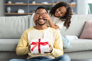 Playful curly daughter making surprise for her father