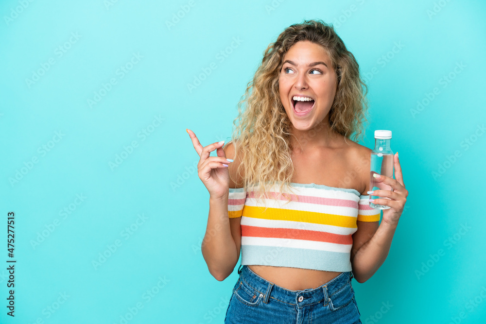 Young blonde woman with a bottle of water isolated on blue background intending to realizes the solution while lifting a finger up