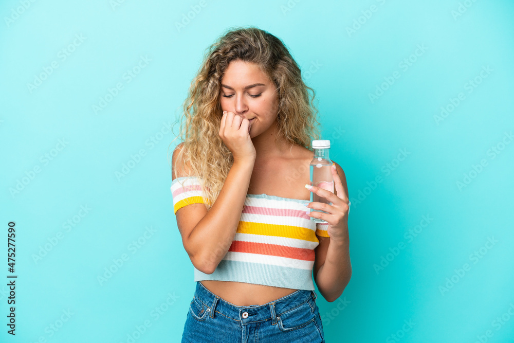 Young blonde woman with a bottle of water isolated on blue background having doubts Young blonde woman with a bottle of water isolated on blue background having doubts