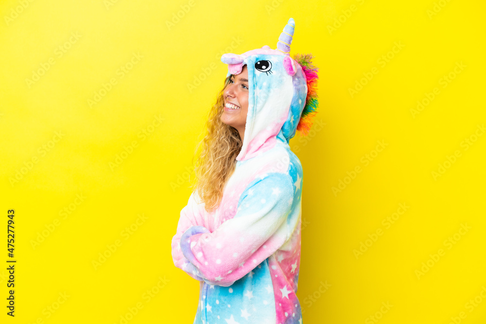 Girl with curly hair wearing a unicorn pajama isolated on yellow background in lateral position Girl with curly hair wearing a unicorn pajama isolated on yellow background in lateral position