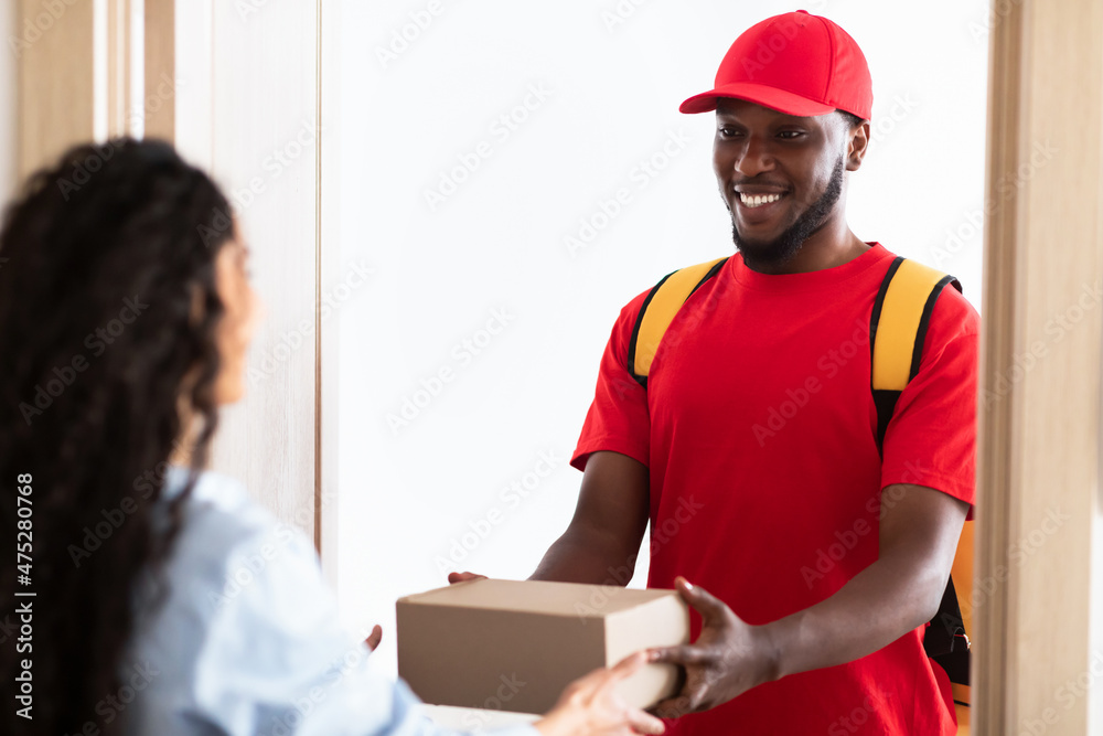 Black delivery man holding box giving it to customer Black delivery man holding box giving it to customer
