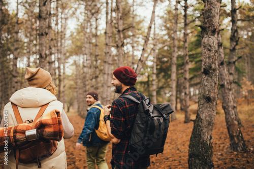 Group of friends travelers with backpacks hiking in a forest. Wanderlust concept.