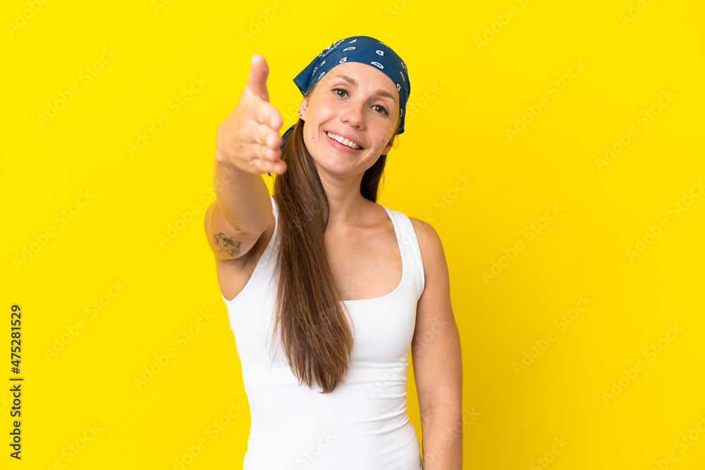 Young English woman isolated on yellow background shaking hands for closing a good deal Young English woman isolated on yellow background shaking hands for closing a good deal
