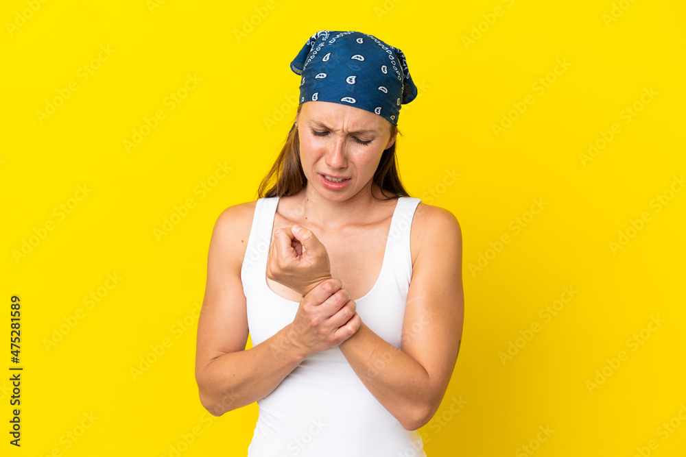 Young English woman isolated on yellow background suffering from pain in hands