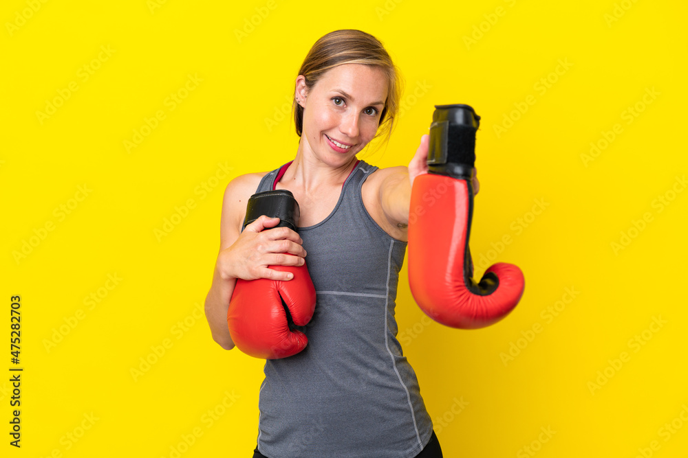 Young English woman isolated on yellow background with boxing gloves Young English woman isolated on yellow background with boxing gloves