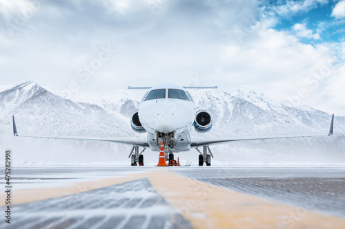 Fotografie, Obraz Front view of the white luxury corporate business jet on the winter airport apro