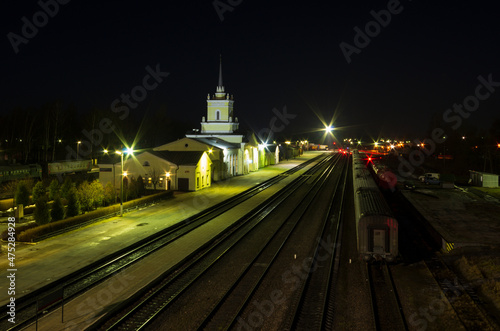 Night landscape of a railway hub with a station building and rays of lanterns (Pskov region, Russia)