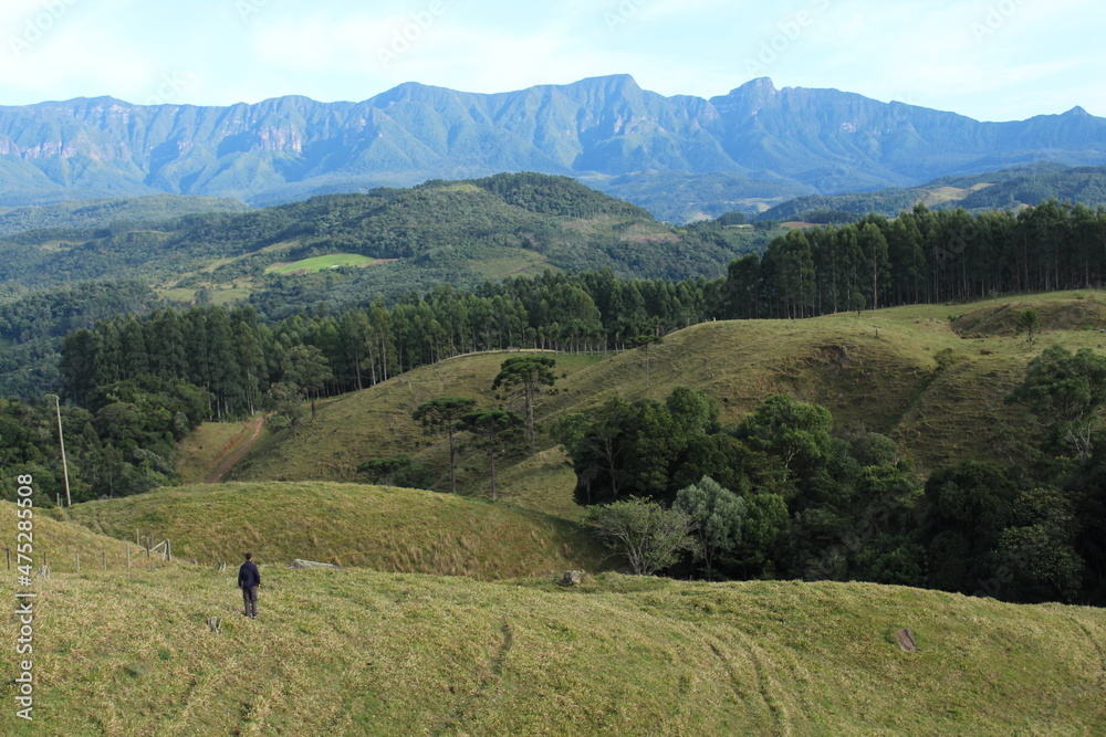 turista não identificado caminhando na grama com montanhas ao fundo em Anitápolis, Santa Catarina turista não identificado caminhando na grama com montanhas ao fundo em Anitápolis, Santa Catarina
