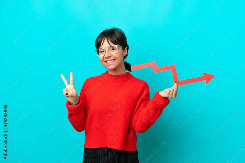 Young woman isolated on blue background holding a catching a rising arrow and celebrating a victory Young woman isolated on blue background holding a catching a rising arrow and celebrating a victory