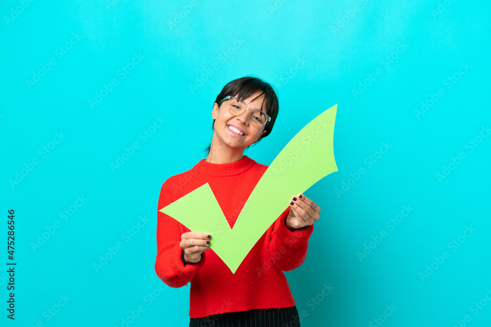 Young woman isolated on blue background holding a check icon with happy expression Young woman isolated on blue background holding a check icon with happy expression