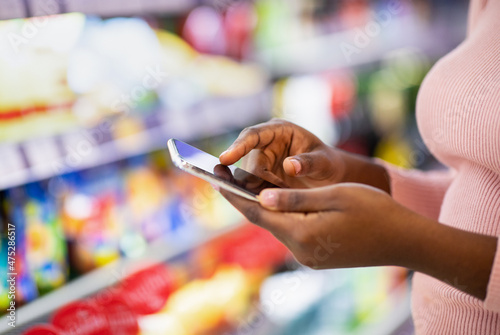 Cropped view of young black woman checking grocery list app on cellphone at supermarket  copy space
