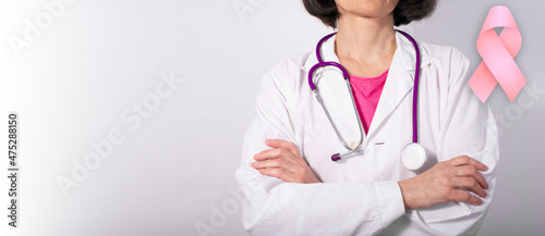Caucasian female confident doctor with crossed arms background with breast cancer awareness pink ribbon