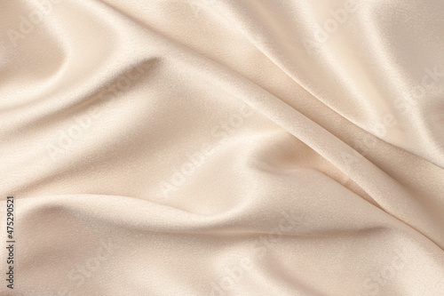 Silk atlas soft tender beige color fabric with shiny curves and waves macro