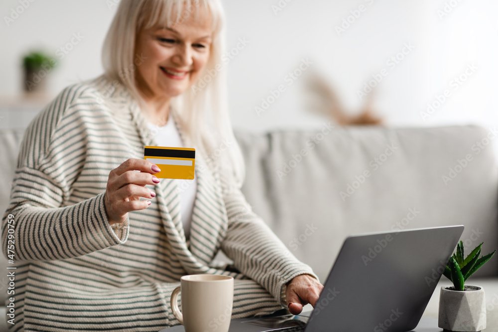 Smiling mature woman showing credit card at home Smiling mature woman showing credit card at home
