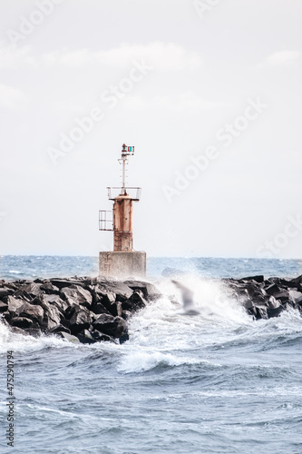 lighthouse on the rocks with waves washing over it