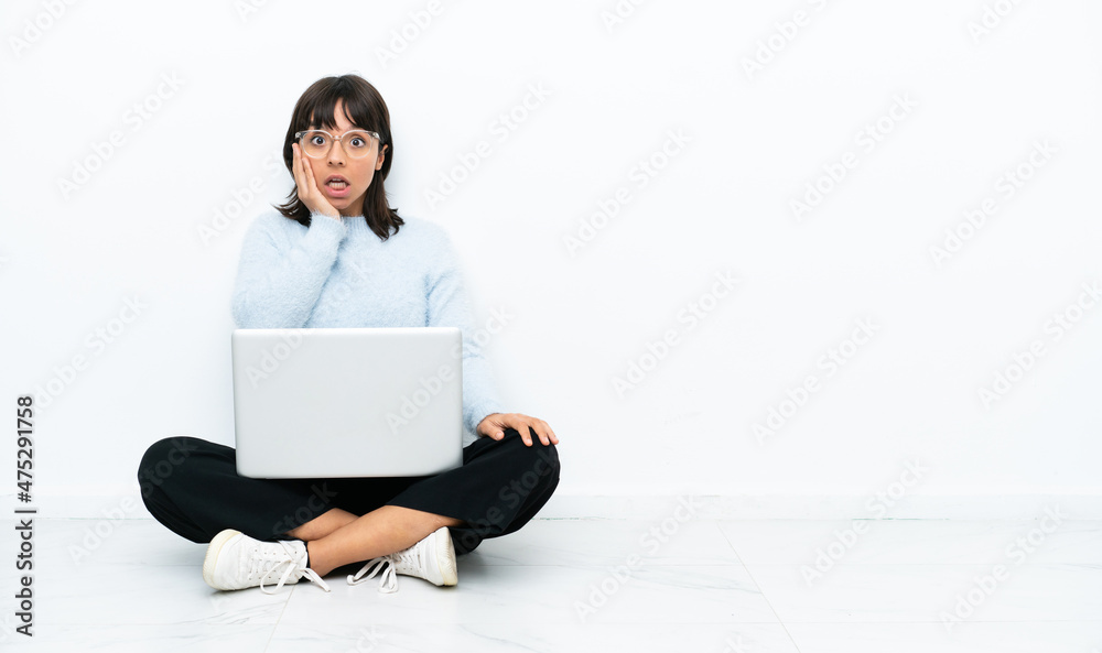 Young mixed race woman sitting on the floor with laptop isolated on white background with surprise and shocked facial expression Young mixed race woman sitting on the floor with laptop isolated on white background with surprise and shocked facial expression