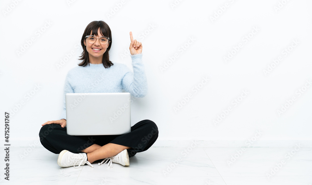 Young mixed race woman sitting on the floor with laptop isolated on white background showing and lifting a finger in sign of the best Young mixed race woman sitting on the floor with laptop isolated on white background showing and lifting a finger in sign of the best