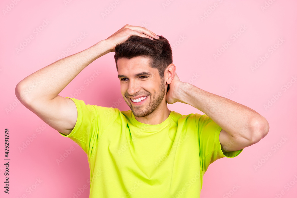 Portrait of attractive cheerful guy touching silky clean fresh hair isolated over pink pastel color background