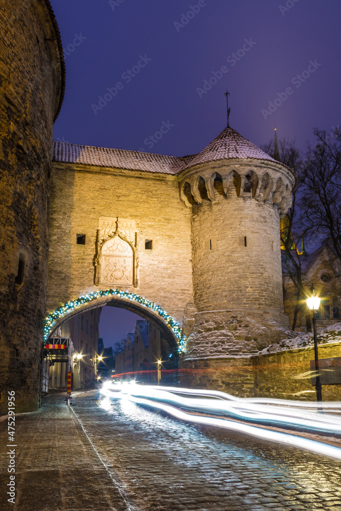 Beautiful long-exposure view of the illuminated Great Coastal Gate, the tower Fat Margaret and the Pikk Street at dusk, Tallinn Old Town, Estonia
