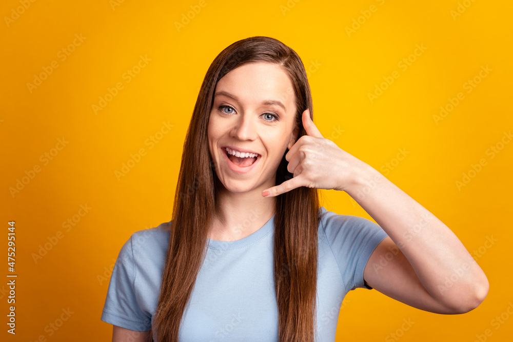Photo of young cheerful girl show fingers call talk symbol conversation isolated over yellow color background Photo of young cheerful girl show fingers call talk symbol conversation isolated over yellow color background