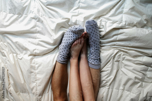couple's feet together with fluffy socks on bed